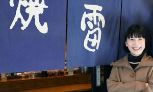 炭焼雷の暖簾の前で微笑む、社長の村井由香(むらゆか)